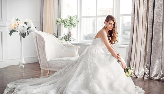 Bride in beautiful Corset Wedding dress sitting on sofa