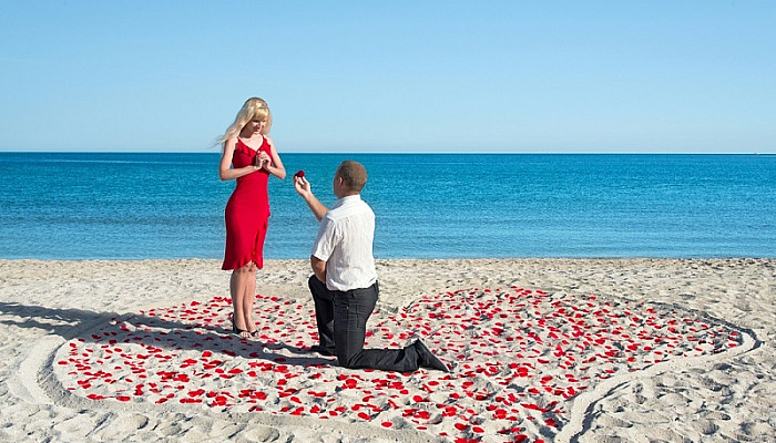 man making proposal with gold ring to his woman near beach