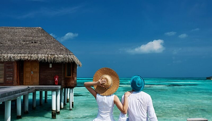 Couple enjoying honeymoon on a tropical beach jetty at Maldives