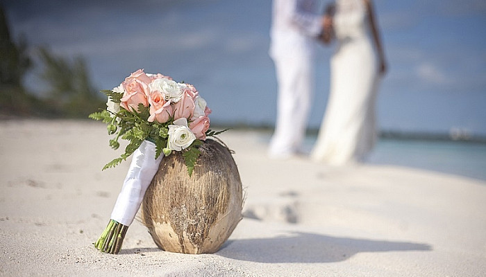 bride and groom on caribbean beach with coconut and wedding bouquet