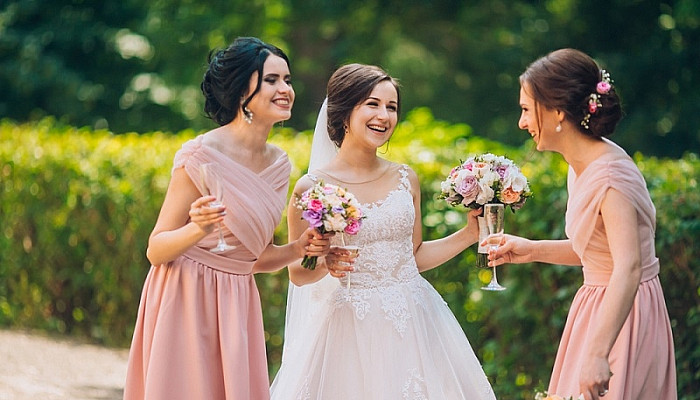 Bride and bridesmaid in nature with bouquets of flowers