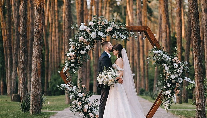 Bride and groom in the forest near a wedding wooden arch