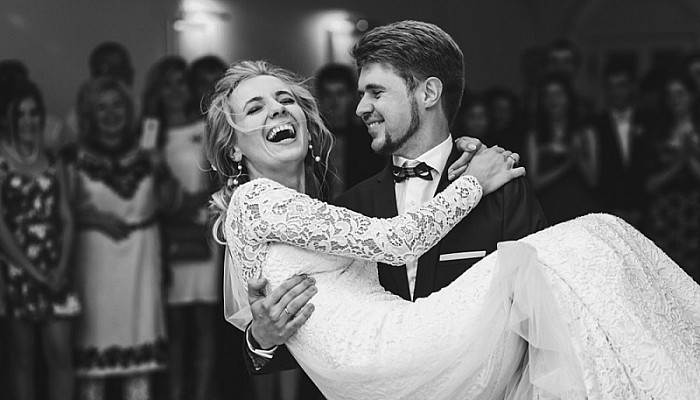 Groom admires happy bride laughing in his arms