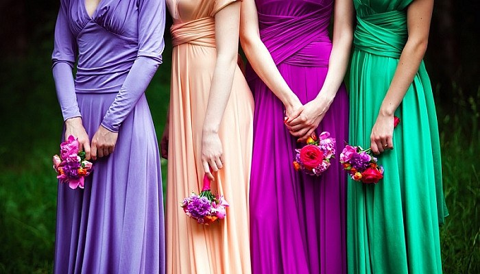 Bridesmaids in colorful dresses with bouquets of flowers