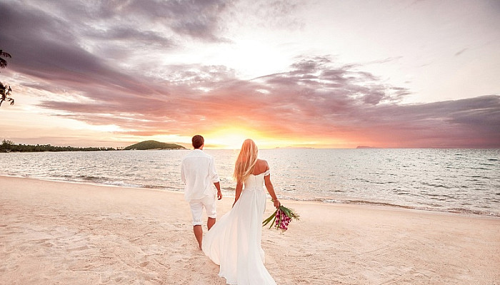 Newlyweds couple holding hands walking near the beach