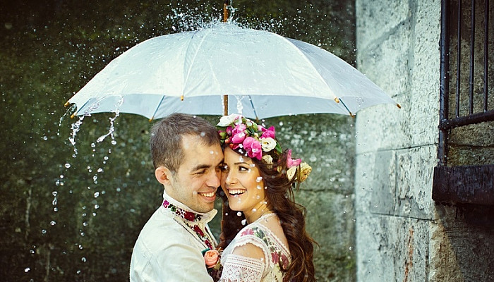  newlyweds in traditional ethnic dress under umbrella