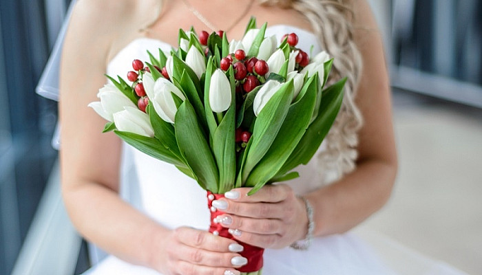 White wedding bouquet of tulips in the hands of the bride 
