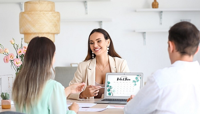 Female wedding vendor discussing ceremony with clients in office