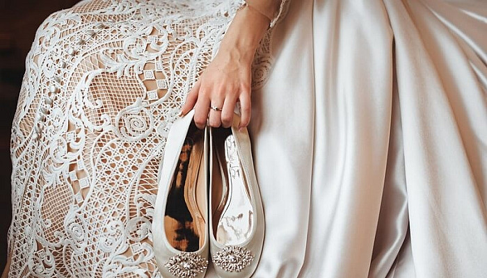 Bride holding flat the wedding shoes