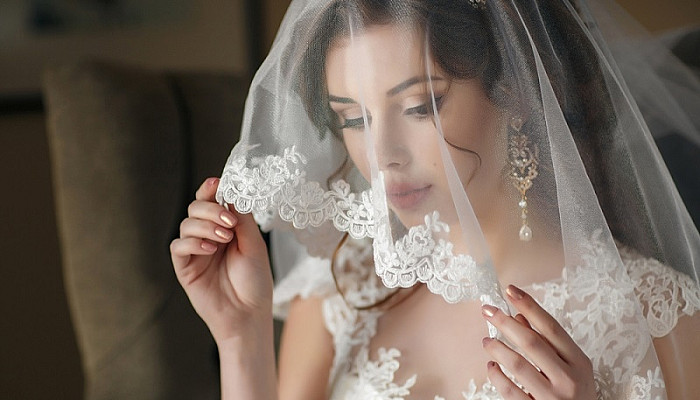 bride in vintage white dress posing under veil