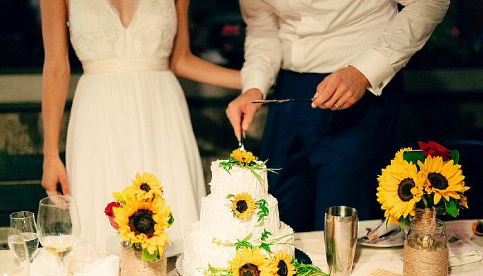 Newly wed couple cutting their Sunflower Wedding Cake