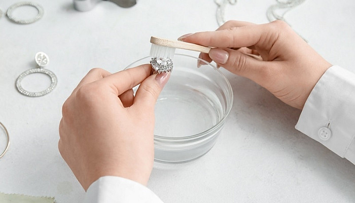 Woman cleaning beautiful Diamond ring with toothbrush